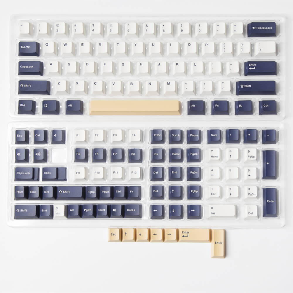 Rudy keycap set shown in its packaging, featuring a joyful and vibrant design with a palette of navy blue and gold colors, combined with intricate details for an engaging and stylish look on your keyboard.